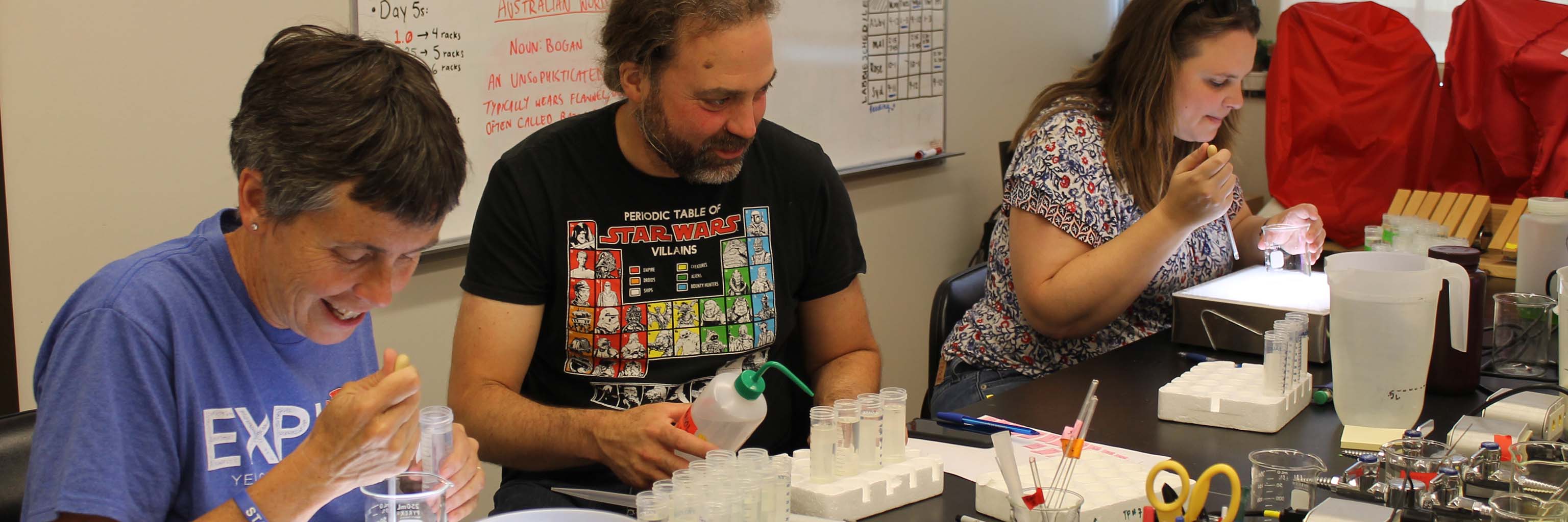 Biology Summer Institute participants pipetting Daphnia in the lab with Professor Spencer Hall (center) at the Indiana University Department of Biology.

