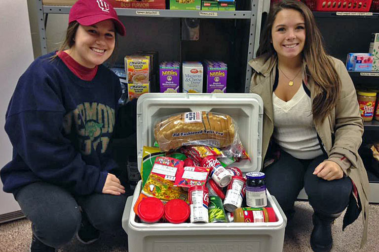 Student volunteers at the Crimson Cupboard display some of the food supply available to those students in need.