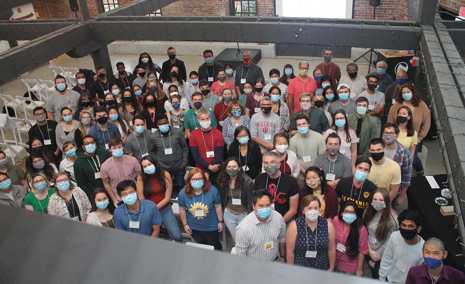 Participants at the 2021 Microbiology Retreat gather for a group photo in an open area of a red-brick building.  All are wearing face masks because of the COVID-19 pandemic.
