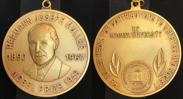 Front and back sides of the gold-colored, round Muller award medallion. Front side: "Hermann Joseph Muller" arching around the top of the medallion, and Nobel Prize 1946 along the lower portion of the medal. A likeness of Muller is etched in the center of the medal between 1890 and 1967, his birth and death years. The text encircling the back side of the medallion reads: The Muller medal for contributions to genetics and society. In the center of the back side:  By Indiana University, an etching of the IU seal, and a space for the recipient's name.