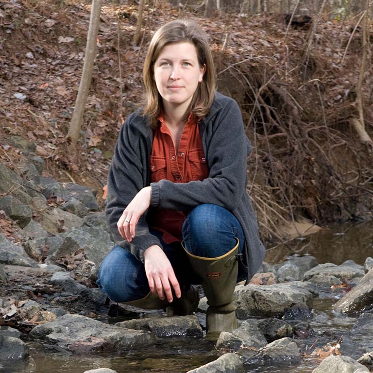Emily Bernhardt in stream in wooded area.