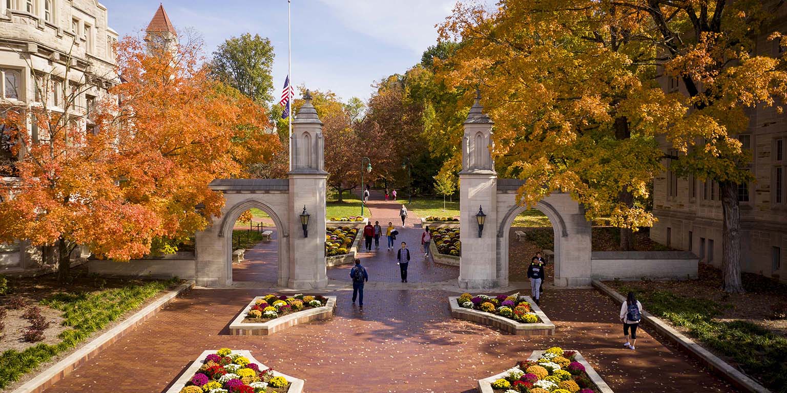 Looking through Sample Gates into the west side of the IU Bloomington campus on a perfect autumn day. Trees are displaying leaves of gold, orange, and red as students walk to classes.