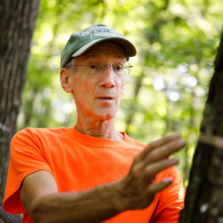 Mark Sheehan gestures near a tree.