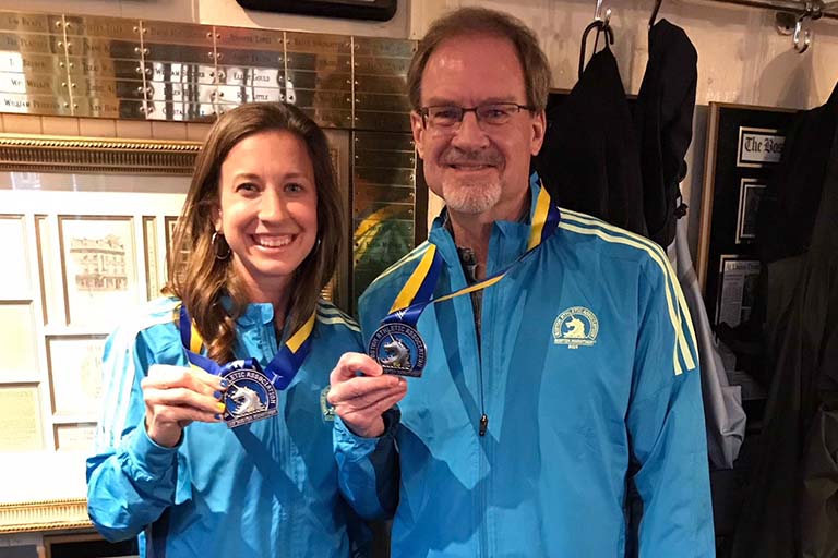 Olivia Ballew and Cliff Huggins show off their medals and jackets after completing the 2019 Boston Marathon.