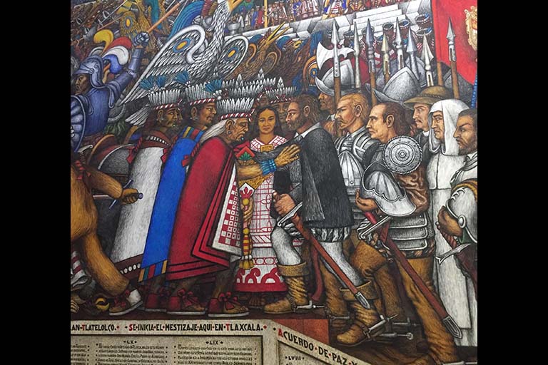 A portion of a panel of a mural at the government palace in Tlaxcala City, painted by Desiderio Hernández Xochitiotzin. This shows Malinche, Cortes, and the Tlaxcalteca leader making an agreement during colonization. These are important murals for Tlaxcala.