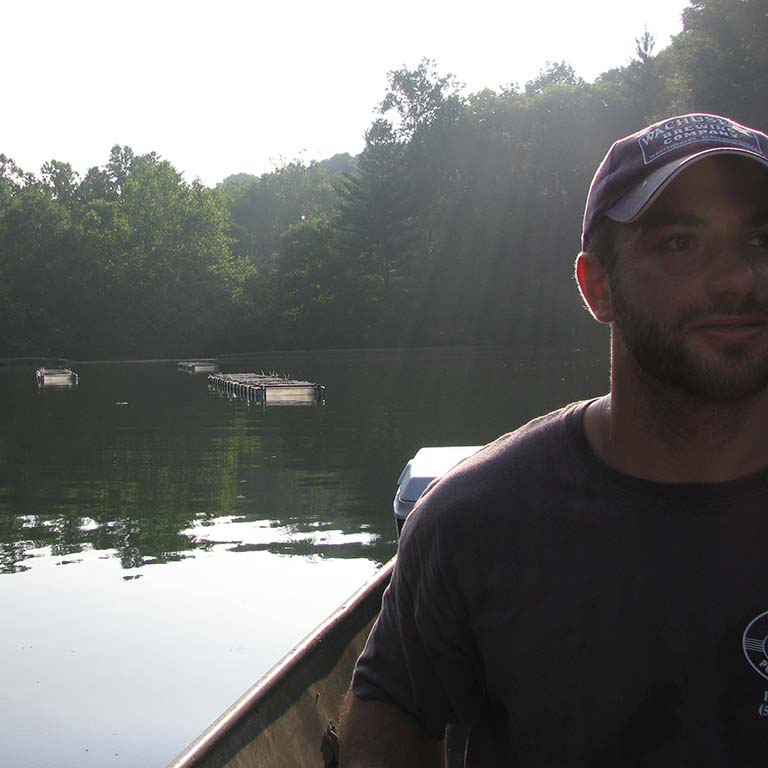 David Civitello in a boat on University Lake at the Indiana University Research and Teaching Preserve Griffy Woods property, checking the Daphnia mecocosms.