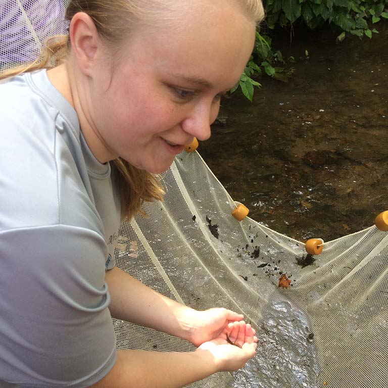 Kara Million holds a darter (a small fish) in her hand that she has just netted from an Indiana stream.