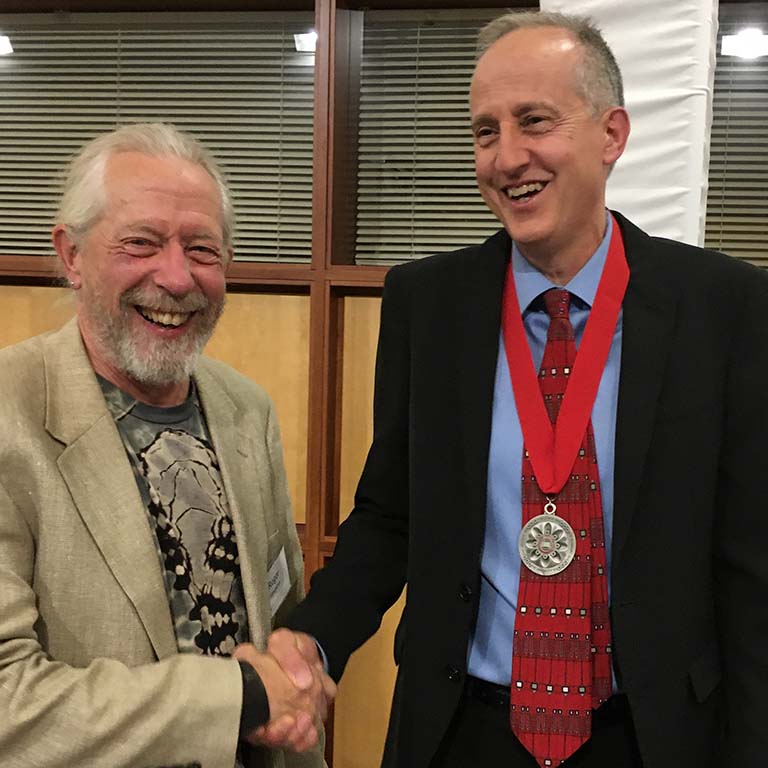 Roger Hangarter shakes hands with Jeff Palmer (right) as he congratulates him in receiving the IU President's Medal for Excellence.