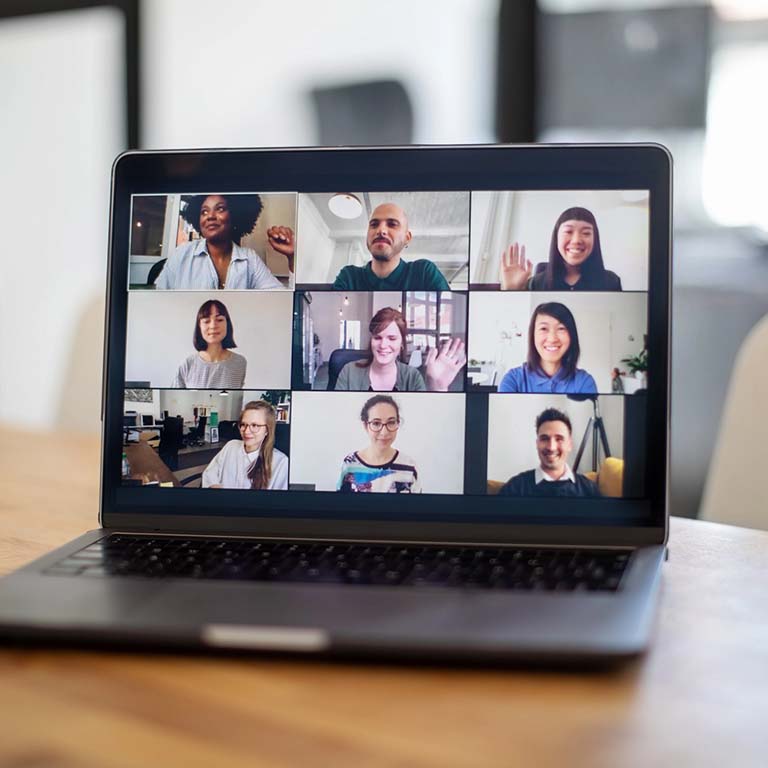 Laptop with nine photos of people in a Zoom meeting.