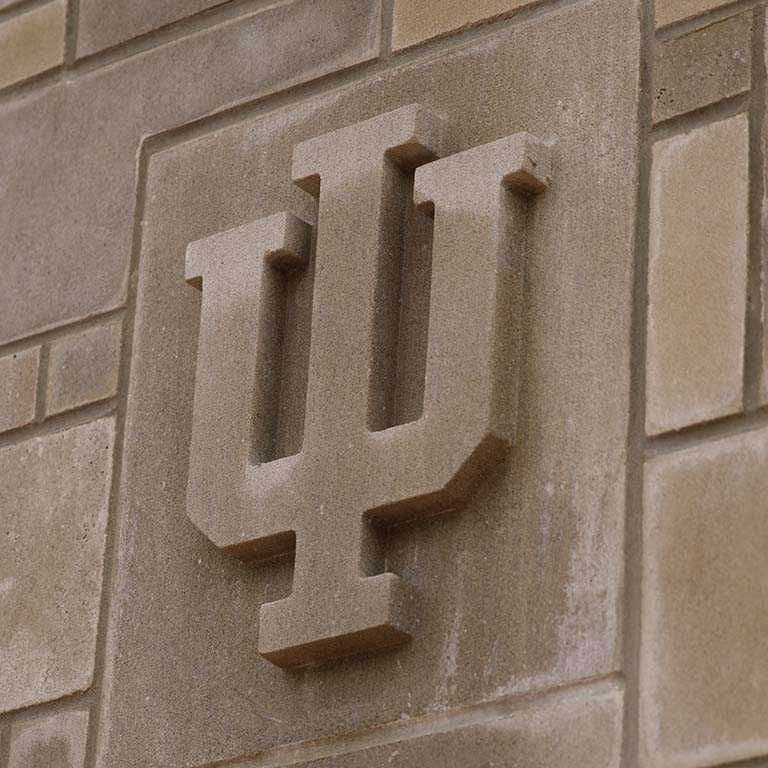 IU trident logo carved in a limestone post on the Indiana University Bloomington campus.