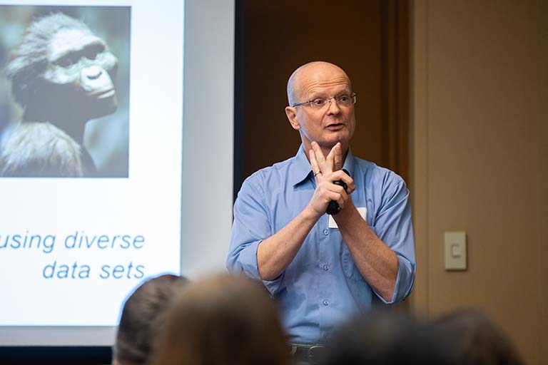 Armin Moczek stands next to a projection of an early hominid on a screen while he presents his successful human evolution teaching module at the National Association of Biology Teachers conference in Chicago in November 2019.
