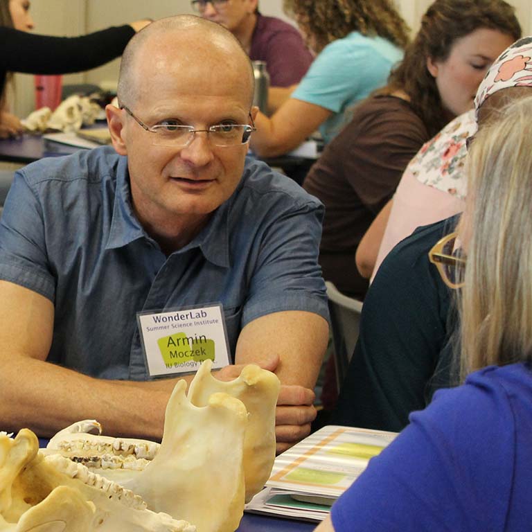 Armin Moczek talks with a teacher during a presentation of his “skulls” module on evolution during a teachers workshop at WonderLab in 2017. Animal skulls are seen on the table.