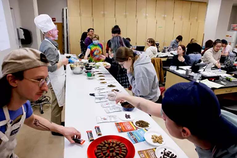 Students make their way through the insect cuisine buffet line. Professor Armin Moczek is seen at left, wearing his chef's hat.