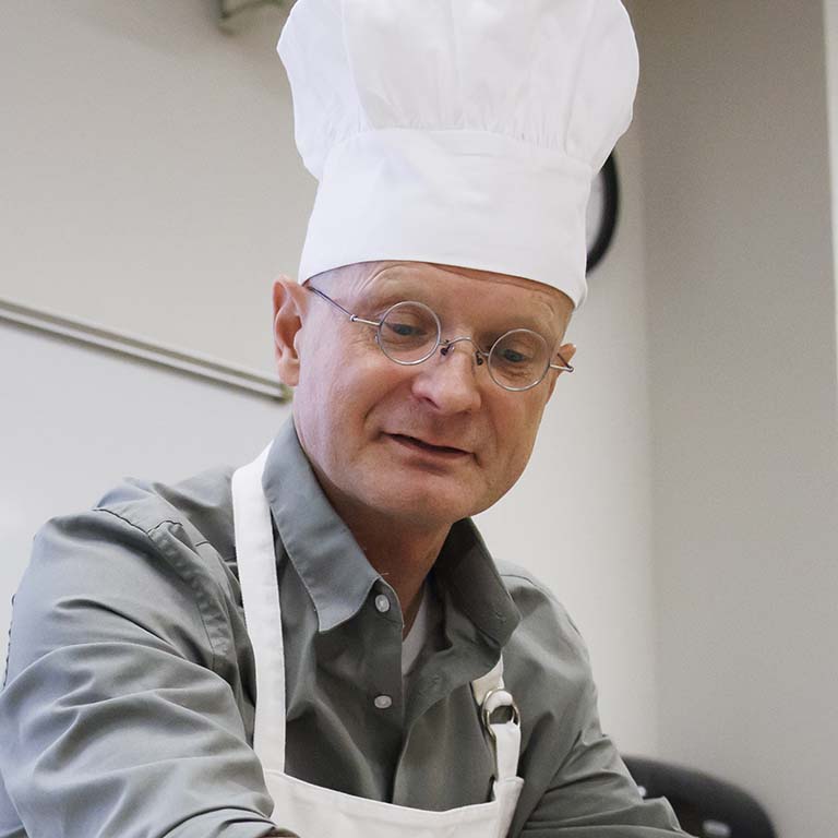 Armin Moczek dons a white chef's hat and apron for the insect cuisine buffet portion of the insect cuisine lab of his entomology class.