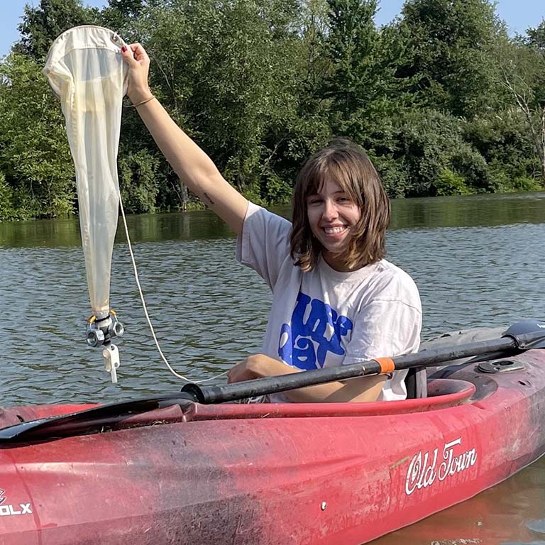 Lauren Albert holds up a long net used to collect zooplankton while she sits in a canoe on Front Lake at the Hillenbrand Fish and Wildlife Area in Indiana.