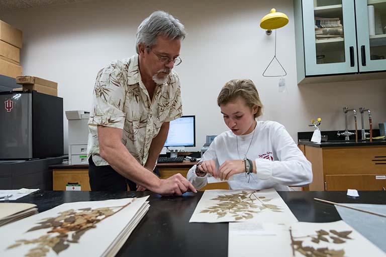 Eric Knox instructs Maggie Vincent on how to affix a label to a specimen sheet.