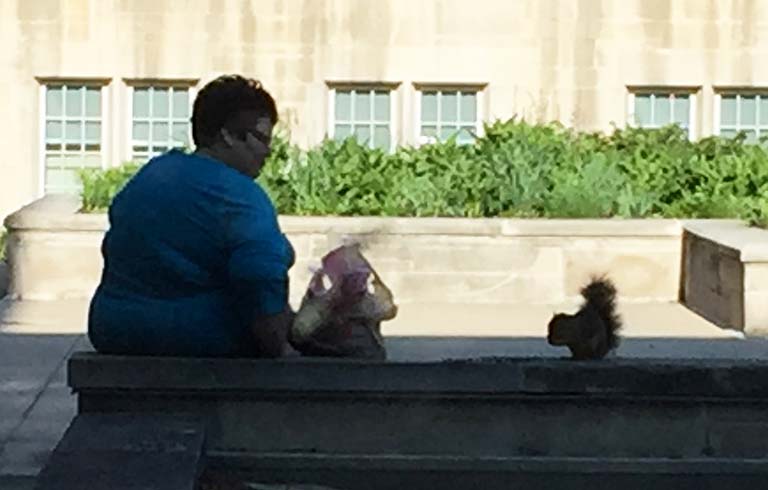 Mary Ann Miller sitting with squirrel outside of Jordan Hall on the IUB campus.