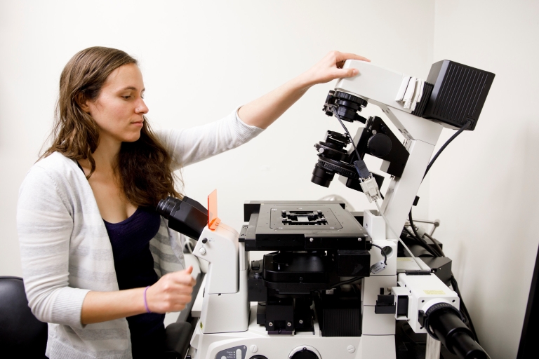 Courtney Ellison adjusts a fluorescence microscope in Jordan Hall.