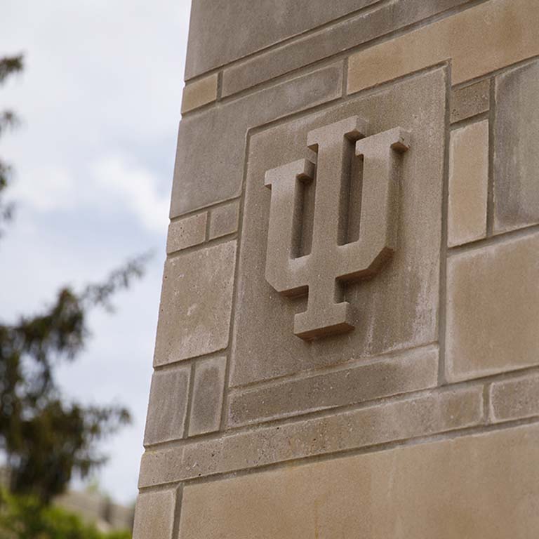 The IU trident is carved in a limestone block pillar.