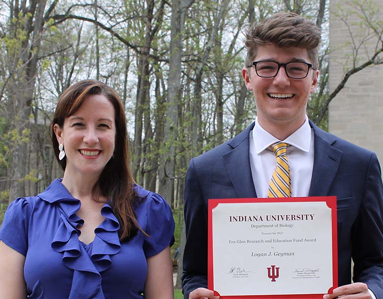Logan Geyman (right) holds his award certificate as he stands next to Julia van Kessel outside of the Biology Building for a picture after the spring 2022 student awards ceremony.