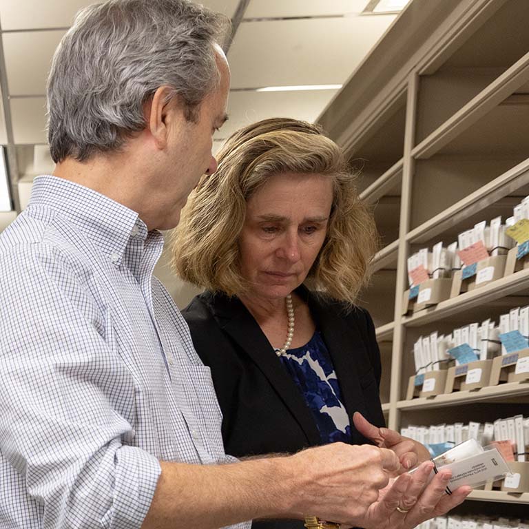 Kevin Cook (left) shows Pamela Whitten one of the living fly cultures in a labeled vial from the rows of shelves in the Bloomington Drosophila Stock Center.